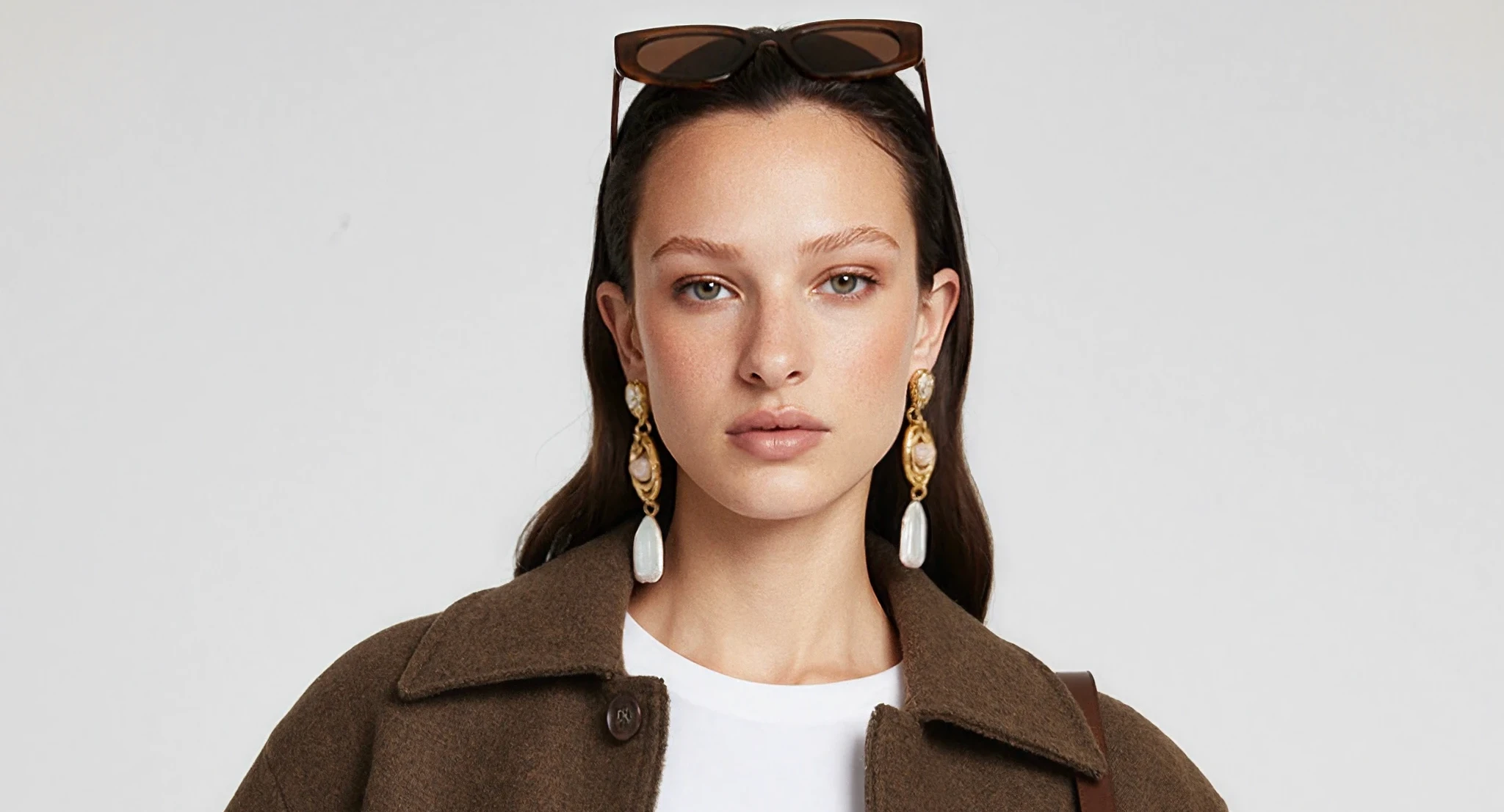 After: sharp AI model portrait in a brown wool jacket, pearl drop earrings and sunglasses, generated with Veeton